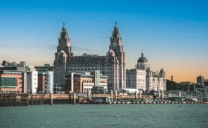 Skyline of Liverpool featuring the Liver Building with its iconic clock towers. The scene is set under a vibrant blue sky, conveying a historic charm.