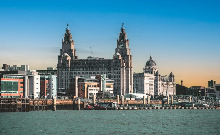 Skyline of Liverpool featuring the Liver Building with its iconic clock towers. The scene is set under a vibrant blue sky, conveying a historic charm.